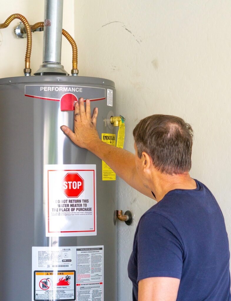 Water heater repair service in West Chester, PA. Man inspecting a Performance water heater, checking for issues and maintenance needs.