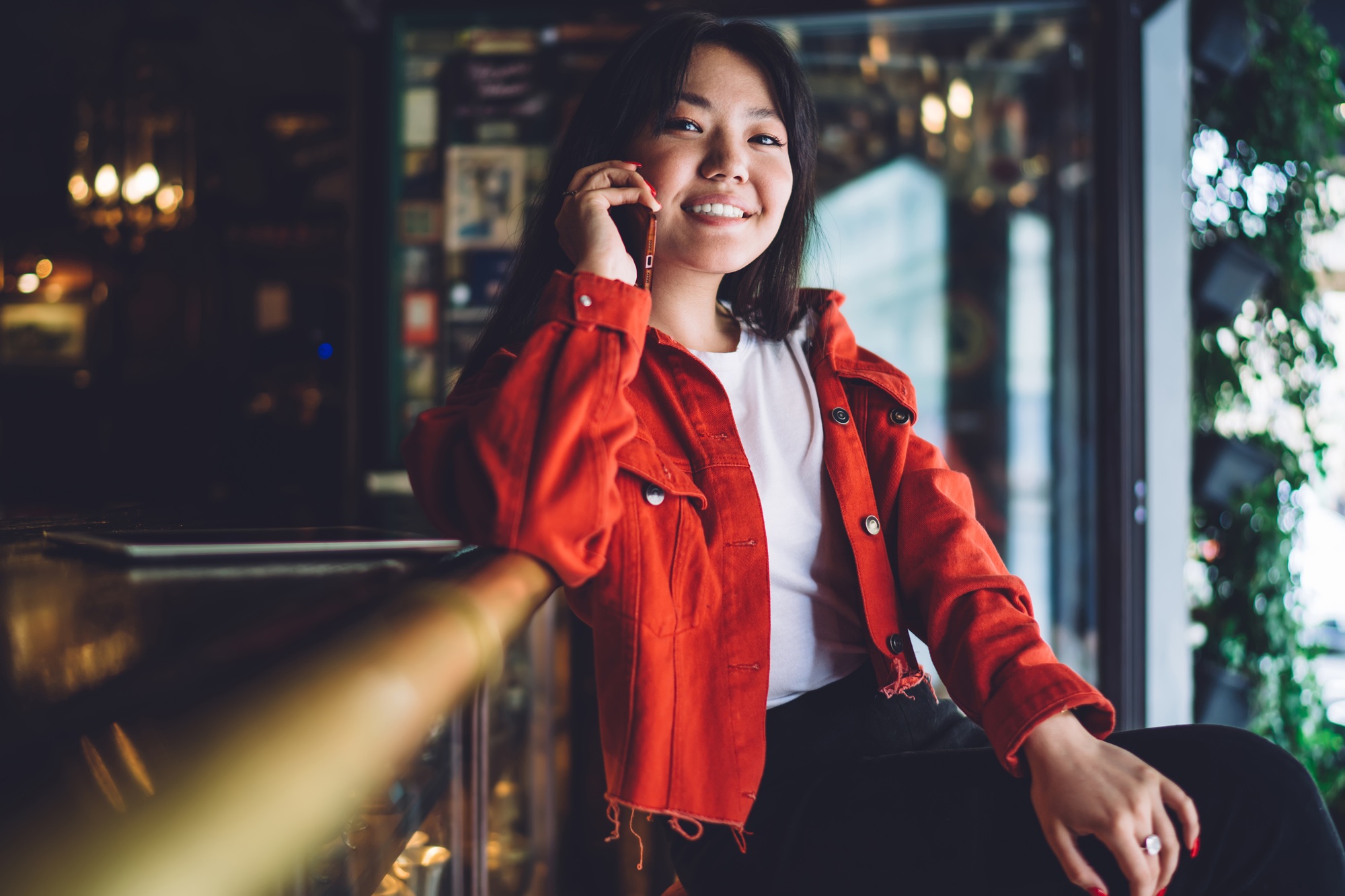 Smiling woman in a red jacket talking on a smartphone. Interior design inspiration. Interior design services in West Chester, PA.