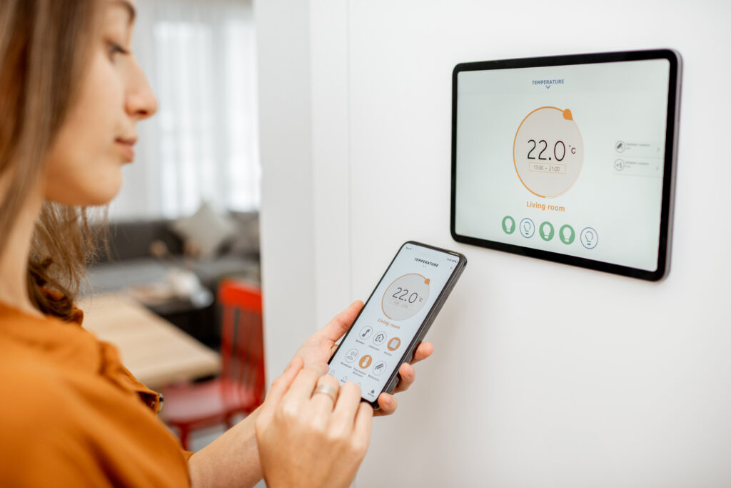 Woman using a programmable thermostat app on a smartphone to adjust the temperature in West Chester, PA. Smart home climate control.