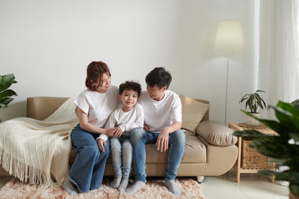 Happy Asian family portrait. Mother, father, and child sit together on a couch. Family counseling in West Chester, PA.