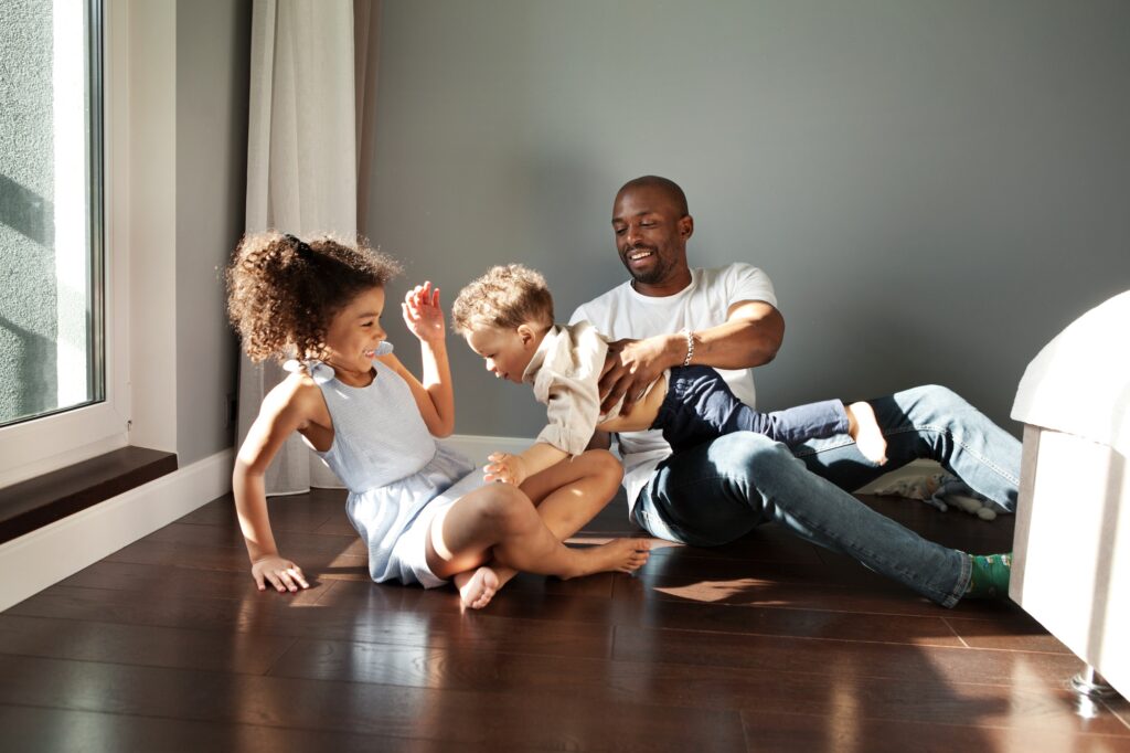 Father playing with his children on the floor. Family time in West Chester, PA. Happy moments and laughter with loved ones.